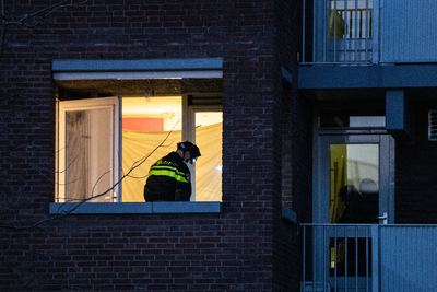 910843 Afbeelding van een politieagent tijdens een huiszoeking in verband met het onderzoek naar de verdachte Gökmen T. ...